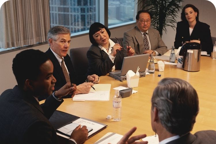 A serious meeting is being held around a conference table.