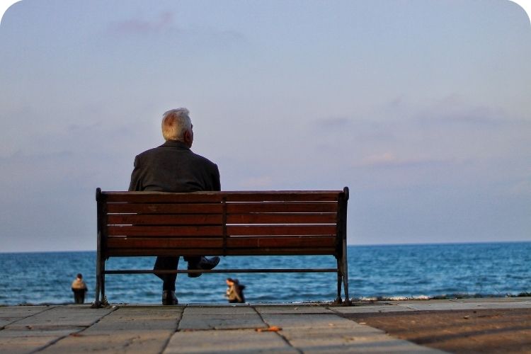 Man sitting on a bench looking at the ocean.