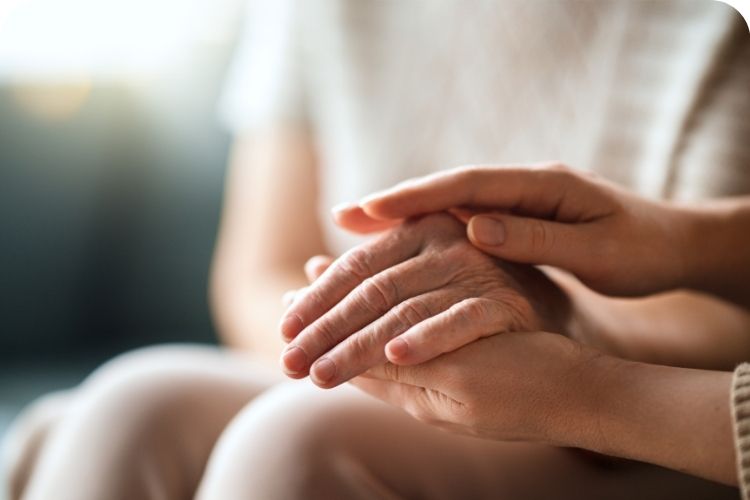 One woman holding the hand of another woman to comfort her.