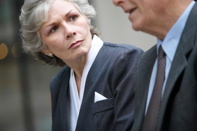 Older business man having a serious conversation with an older businesswoman.