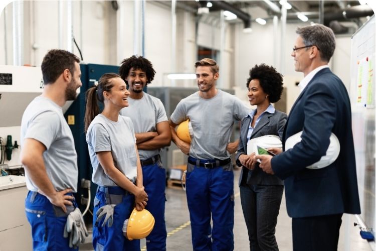 A team meeting on the factory floor with happy employees.