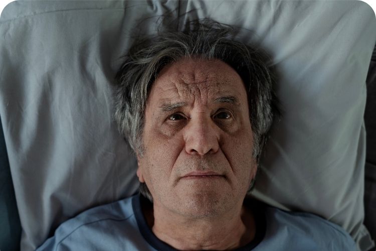 Tired man lying awake in bed.