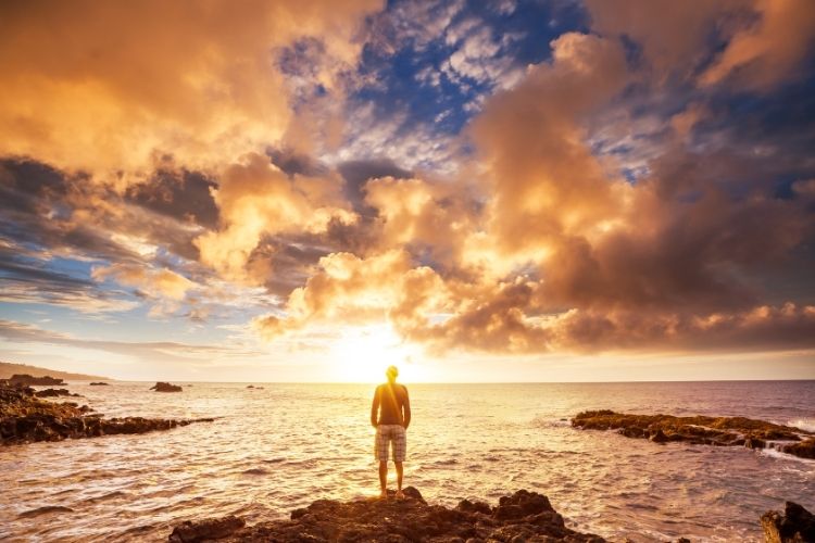 A man staring into a beautiful sunset.