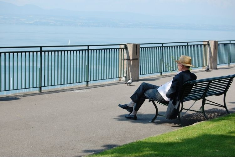 Man sitting on a bench looking out at the beautiful ocean.