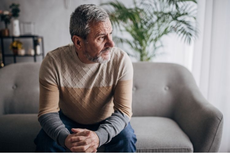 A depressed man sitting on a couch.