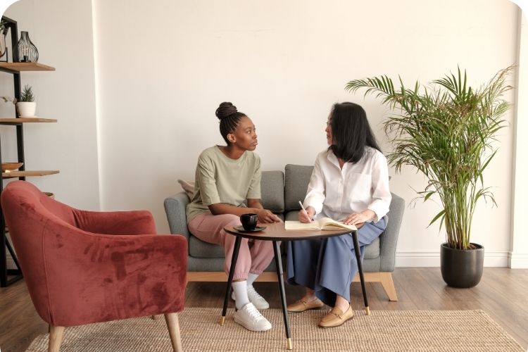 Two women talking together on a couch.