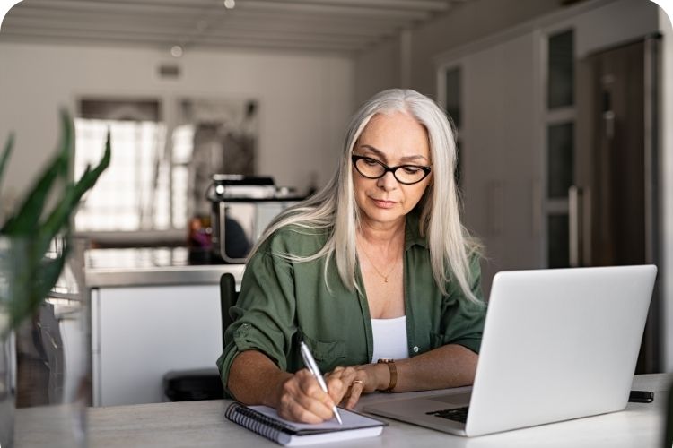 A woman working at her desk writing down notes.