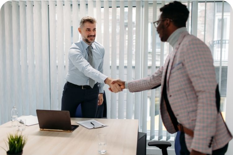 Two men shaking hands in a meeting room.