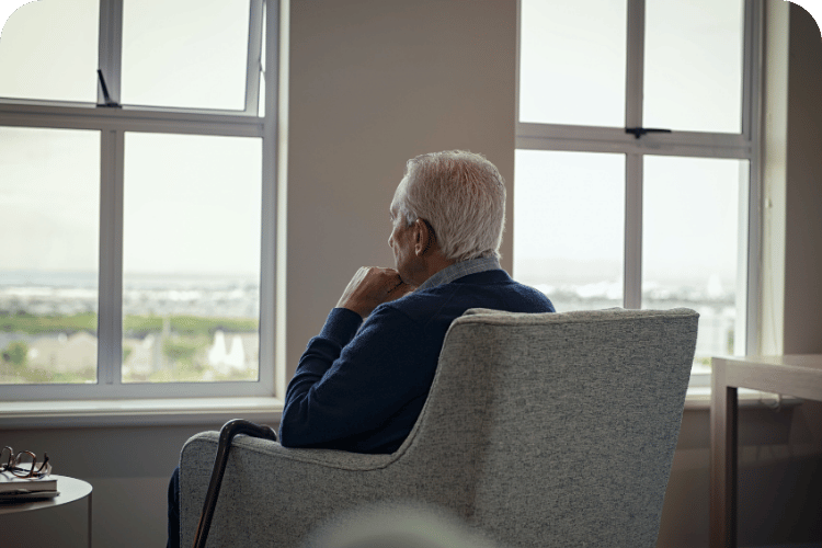 An older man sitting by the window in contemplation.