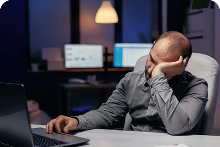 A tired man at his desk working late into the night.