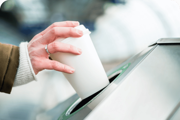 Lady throwing away her coffee cup.