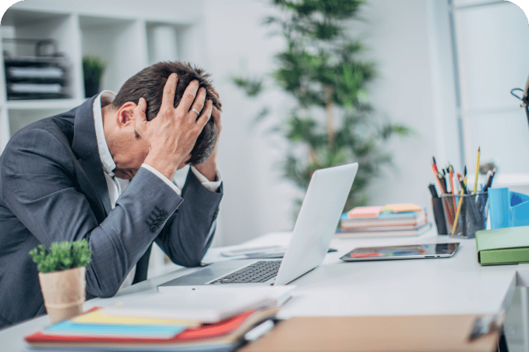 A stressed business leader at his desk with his head in his hands.