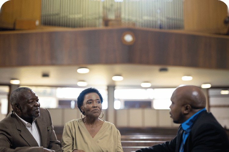 A pastor talking to two members of the church.